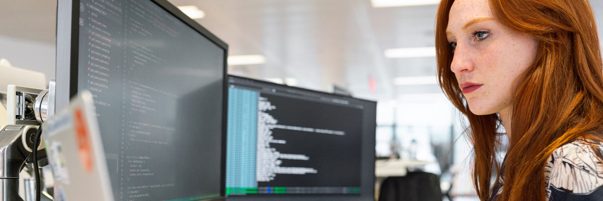 Developer writing code on a desktop monitor in a modern office