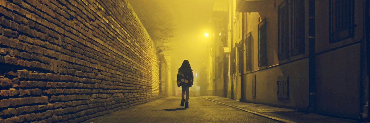 person walking down alleyway at night