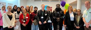 Group photo of ELATT staff and students standing together at ELATT Job Fair event, smiling in front of banners and colourful balloons.