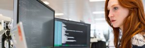 Developer writing code on a desktop monitor in a modern office