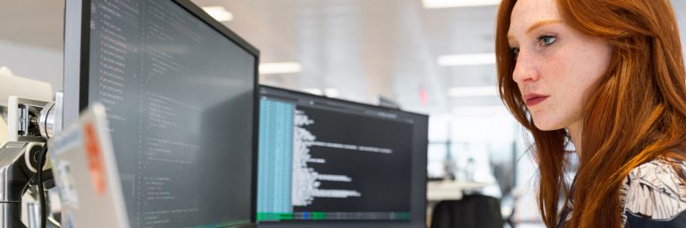 Developer writing code on a desktop monitor in a modern office