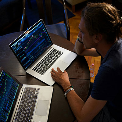 man-looking-at-two-laptops-with-code